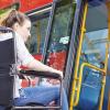 A lady in a wheel chair boarding a bus